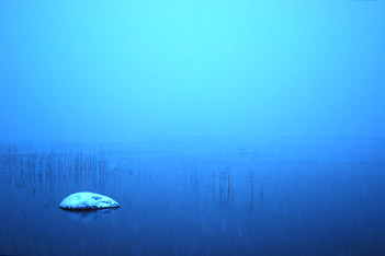 Photo shows a snowy piece of rock in the lake under foggy morning at Villa Cone Beach.