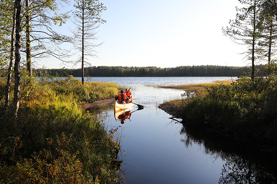 Photo shows two young people canoeing at Villa Cone Beach. Only them at sight.