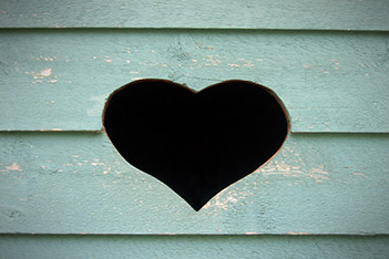 Photo shows a heart figure cut in the wall of a wooden building, as a symbol of friendship and love.