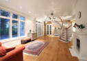 Photo shows Villa Cone Beach living room seen from the dining area, the curved stairscase, oriental carpets and the view through the window to the garden.