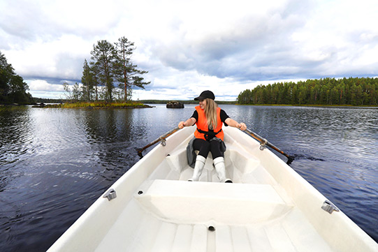 Photo shows a young woman rowing a white boat across the protected Lake Kuivajarvi. No one is at sight.
