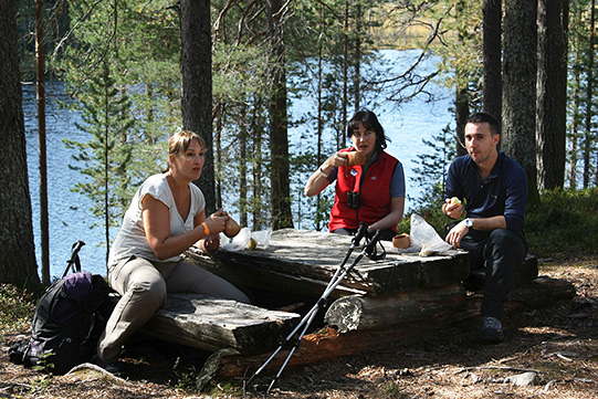 Photo shows young people having a coffee break at their summer picnic in front of a small wilderness lake.